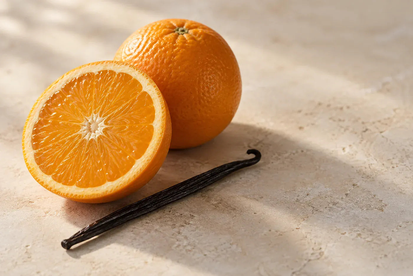 Sweet orange and a vanilla pod on a warm stone surface